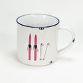 Vintage Keramiktasse im Emaille-look mit einem paar rosa-roten Ski